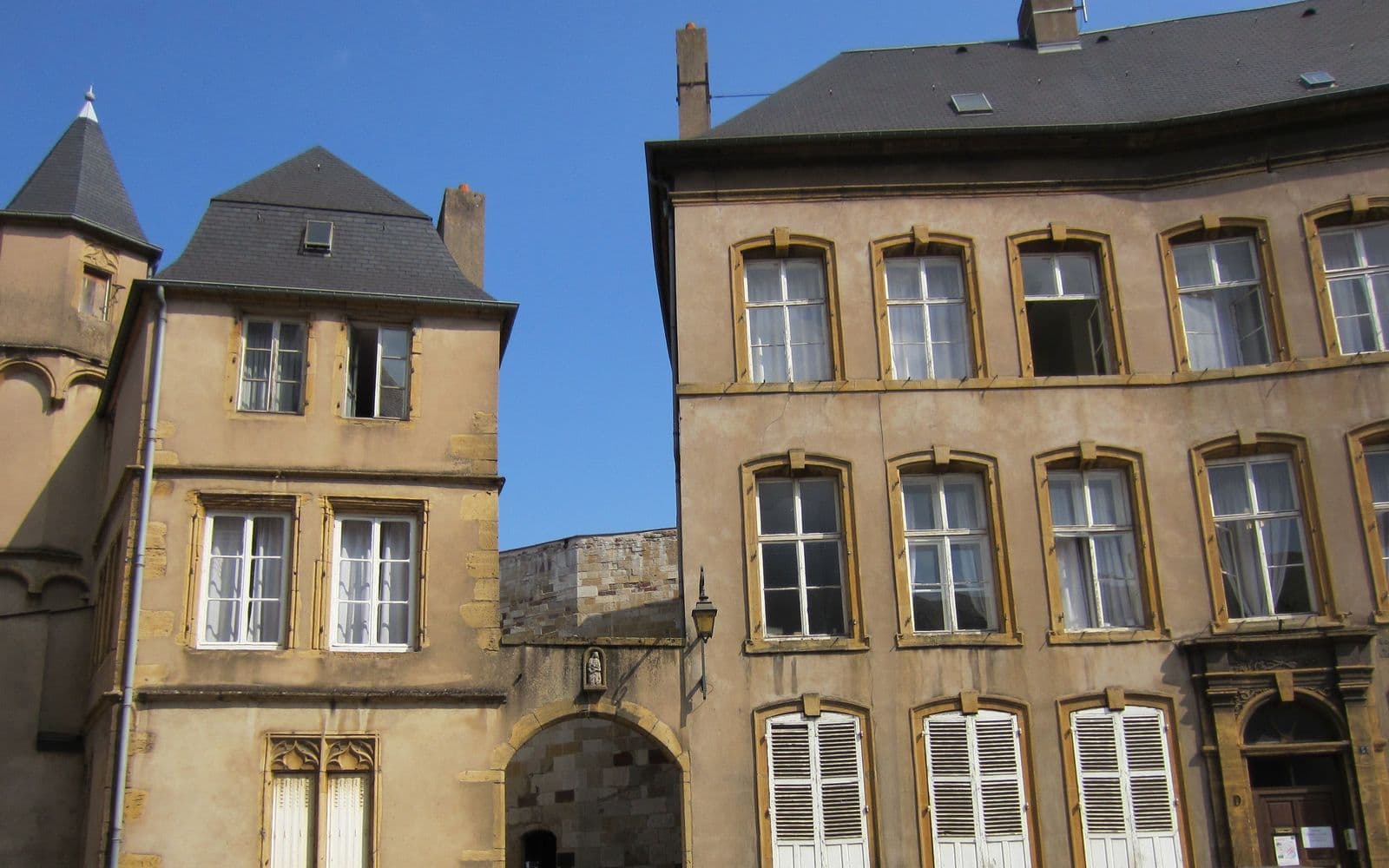 Façades en pierre jaune d'immeubles anciens du centre de Thionville, toits d'ardoise et fenêtres à encadrement jaune